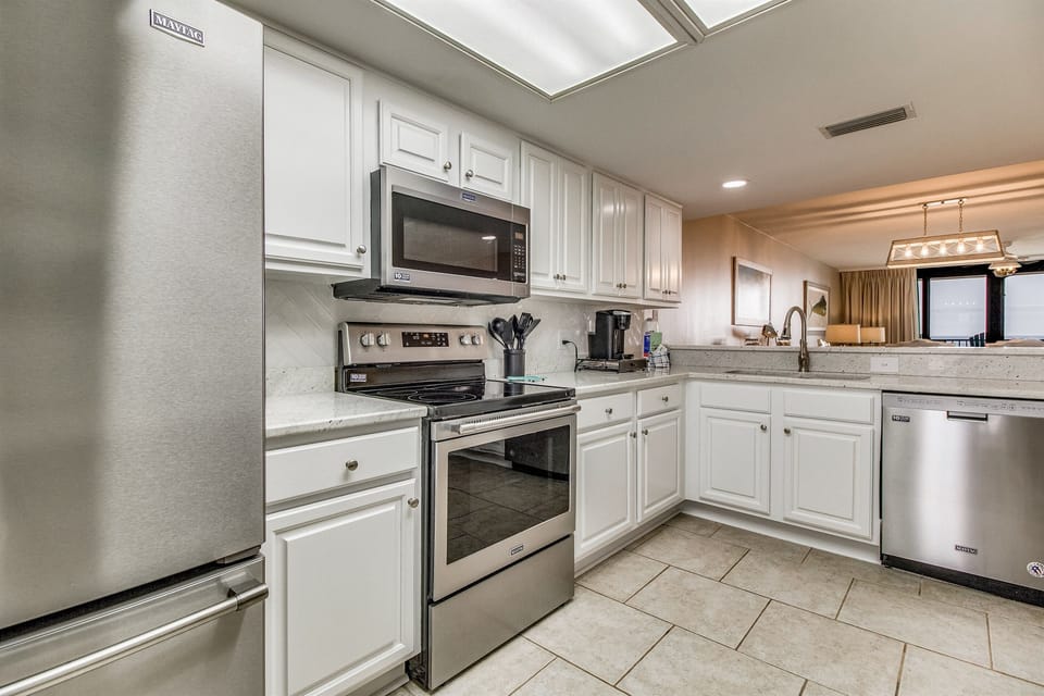 Kitchen with white cabinetry and stainless appliances at Wind Drift Orange Beach
