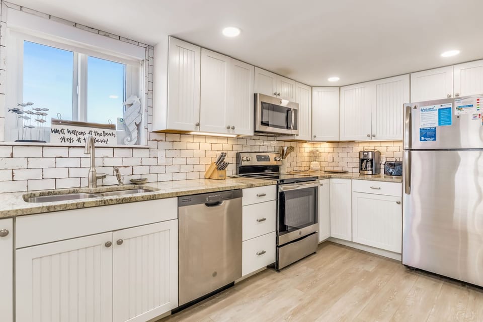 White kitchen with granite countertops and island at Wind Drift Orange Beach