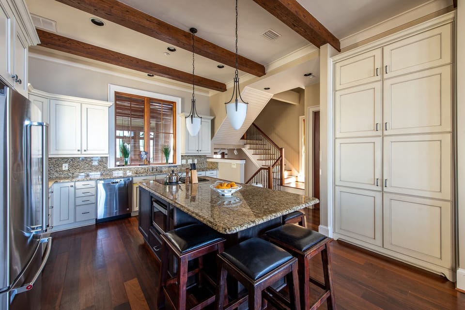 Pantry Doors, Kitchen Island with Stools, Refrigerator, and Dishwasher.