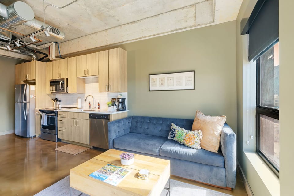 Sink into the plush blue sofa in your open-concept space, where modern industrial charm meets cozy comfort.