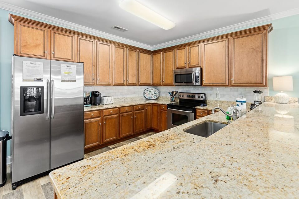 Your fully equipped kitchen invites culinary adventures with granite counters, stainless steel appliances, and warm wood cabinets.