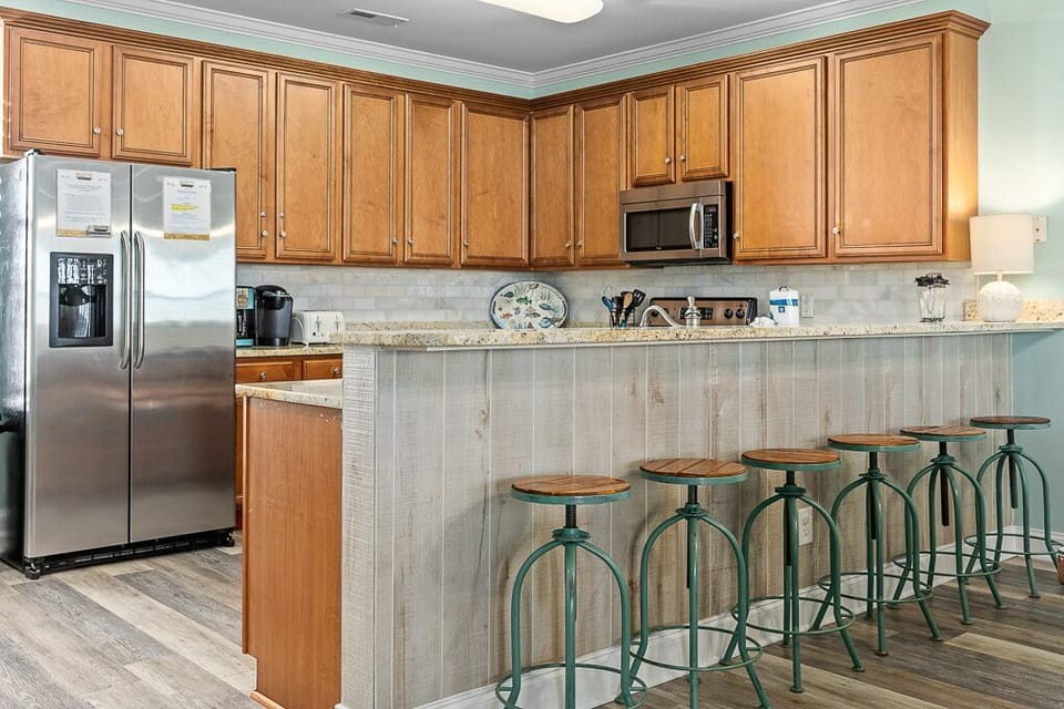 Your spacious kitchen welcomes you with warm wood cabinets, modern appliances, and a breakfast bar perfect for morning coffee or casual meals.