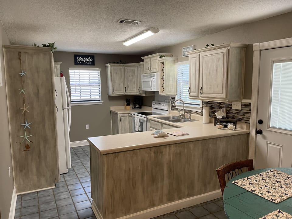 full kitchen with lots of custom chalk painted cabinets and large counter top