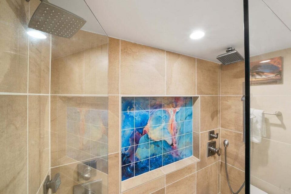 Close‑up of the shower area highlighting the dolphin mural and modern showerhead, a playful detail in a polished space.