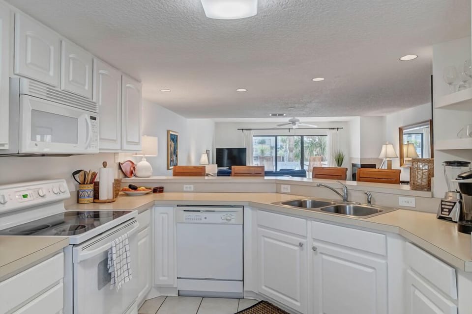 - Cook with a view in this cheerful white kitchen with bar seating and open layout
- Stove, microwave, dishwasher, and dual sink make every meal a breeze
- Connect with guests in the living room while preparing drinks or snacks