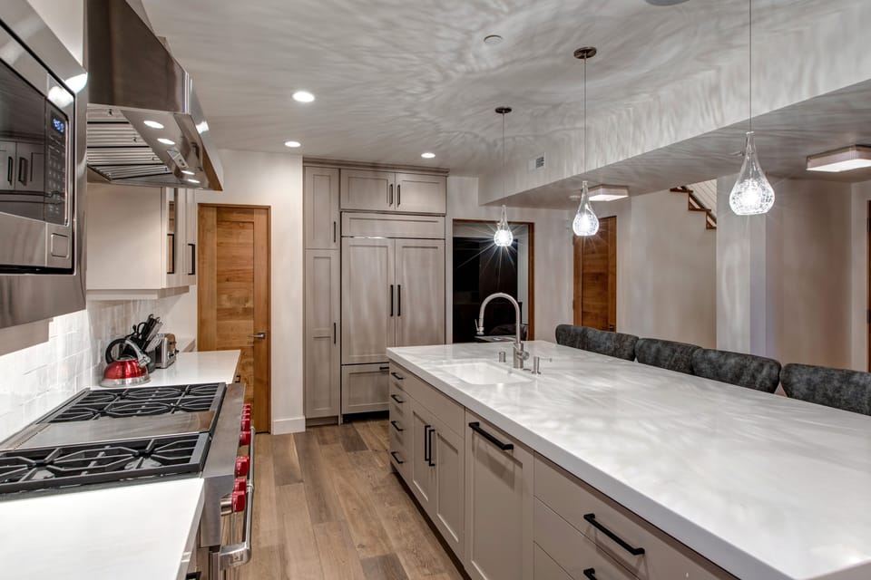 Prepare meals in our fully equipped kitchen, featuring a large island with seating, modern stainless steel appliances, and stylish wood accents. All the essentials for a great stay.