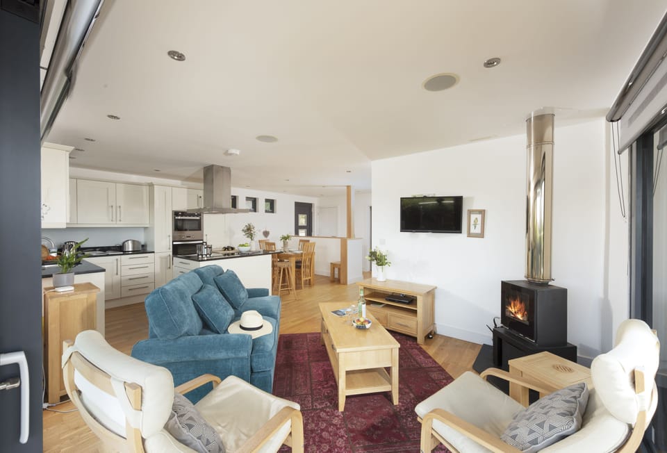 Sea Gem, St Agnes. Sitting area with a television and state-of-the-art wood burning stove. Bi-folding doors to deck