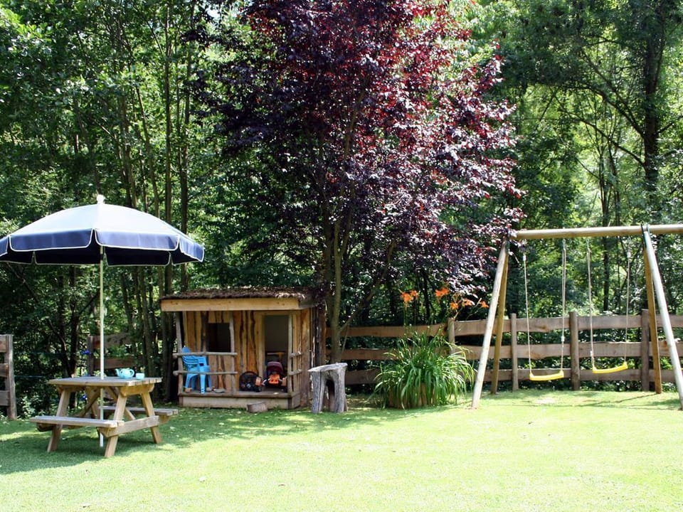 Fenced child-friendly garden with swings, picnic table and toys