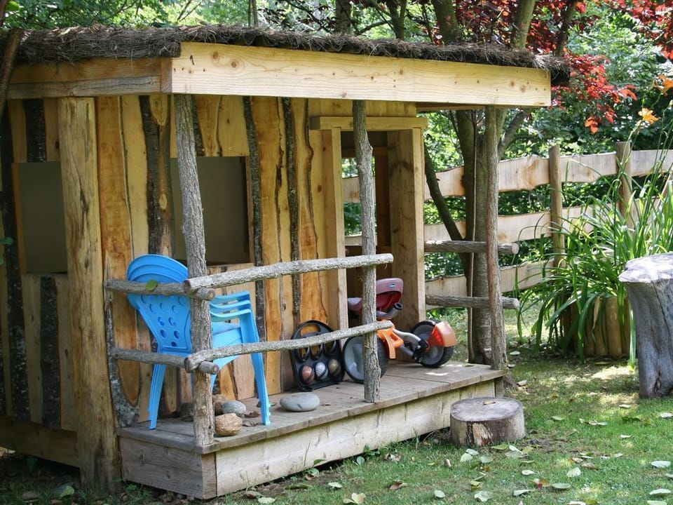 Home-made house for children with swings and picnic table set in a mature garden