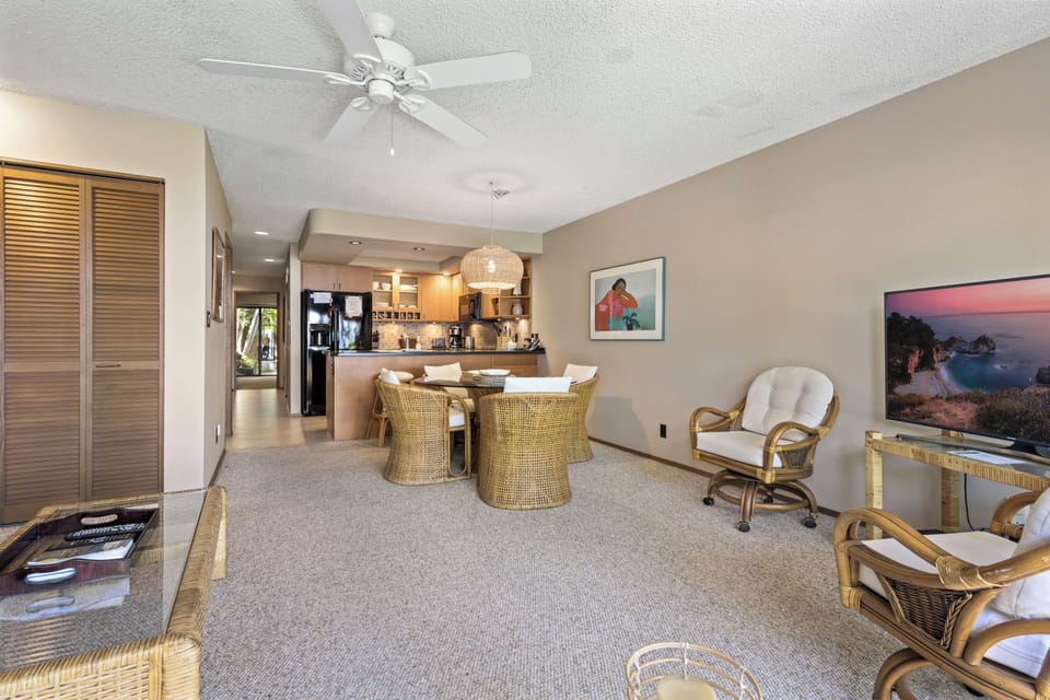 Step into your coastal retreat, where ceiling fans cool your afternoons and woven seating invites relaxation. The open layout flows seamlessly into the kitchen, creating a welcoming space for your vacation.