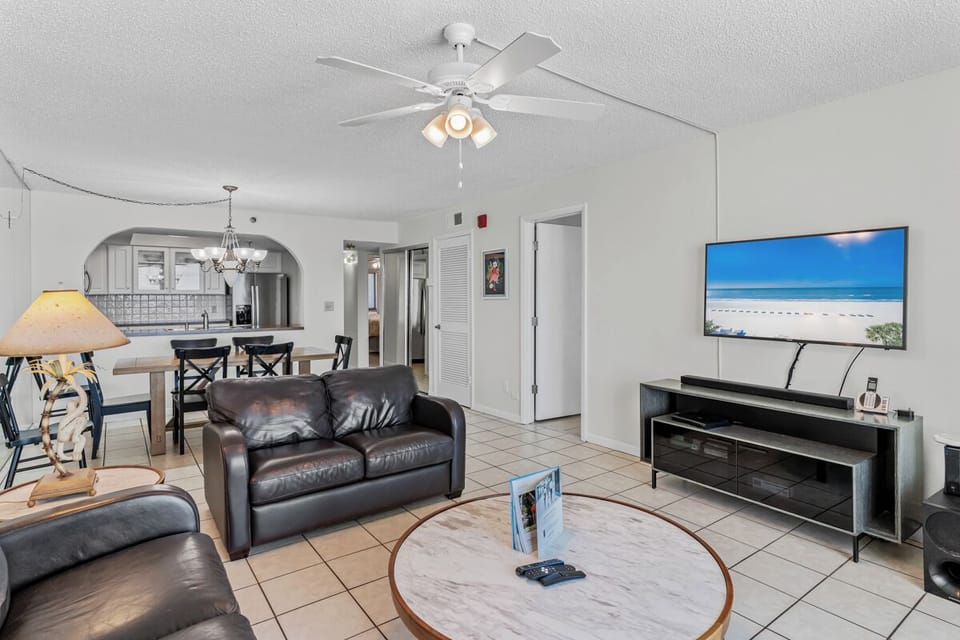 Unwind in your spacious living area with plush leather seating, entertainment center, and open kitchen - perfect for your beach getaway relaxation.