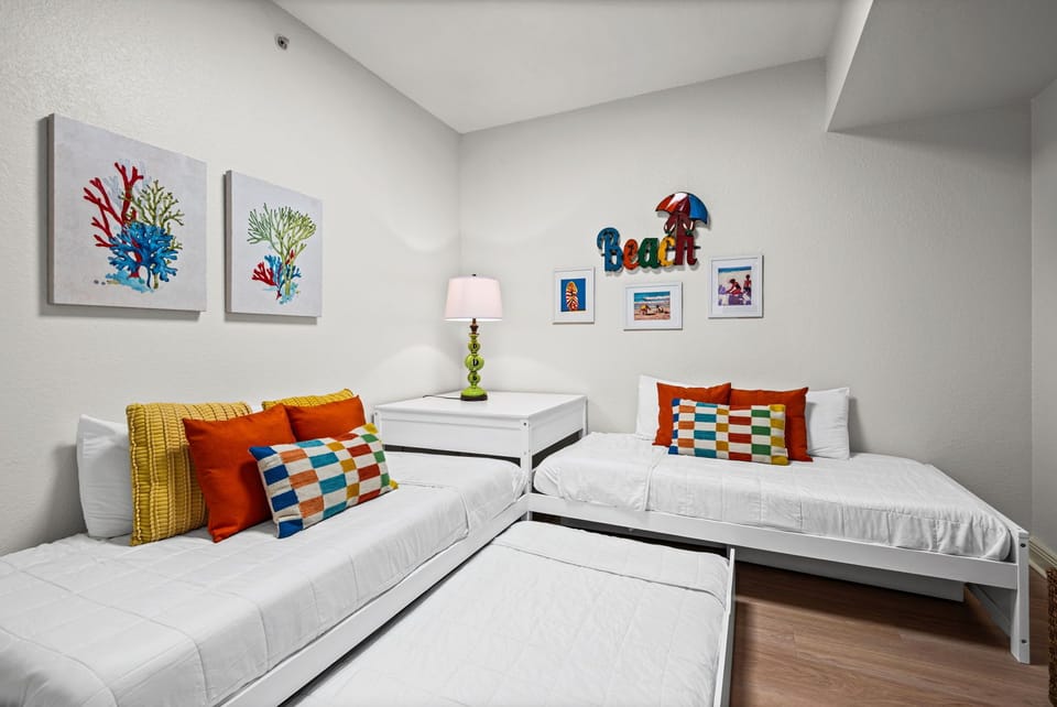 Two twin beds dressed in crisp white linens with vibrant coral and yellow accents await your family.