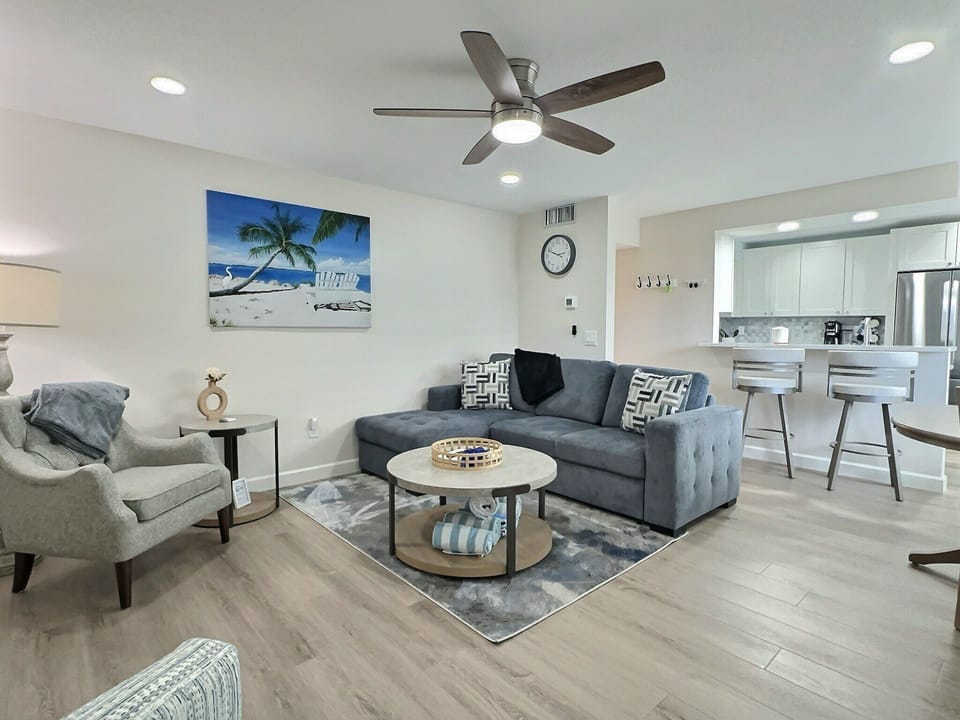 Open-plan living and dining area with sofa, seating, and kitchen in background
