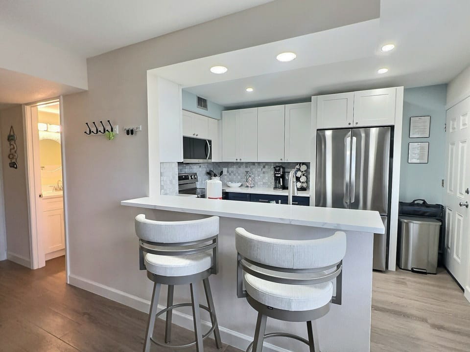 Updated kitchen with island bar seating, stainless appliances, and white cabinets