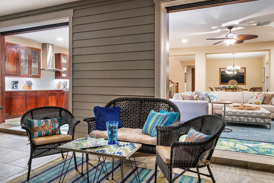 Wicker furniture on the lanai with a view inside the home.