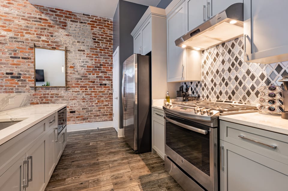 Galley-style, fully equipped kitchen with an open flow to the living/dining area. Stocked with essentials from mixing bowls to wine glasses, featuring stainless steel appliances, stone countertops, and a tile backsplash for a touch of luxury!