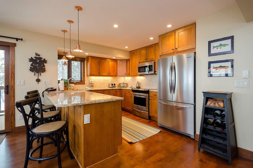 Your fully equipped kitchen features warm wood cabinets, granite counters, and stainless steel appliances perfect for preparing memorable meals during your stay.