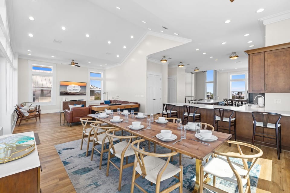 Your open-concept living space combines dining, kitchen, and lounge areas with soaring ceilings and natural light streaming through expansive windows.