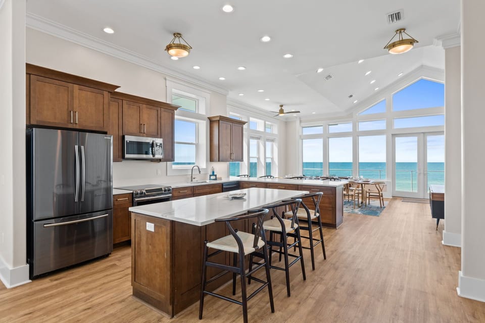 Cook with stunning ocean views through floor-to-ceiling windows. Your fully equipped kitchen features stainless steel appliances and spacious island perfect for meal prep.