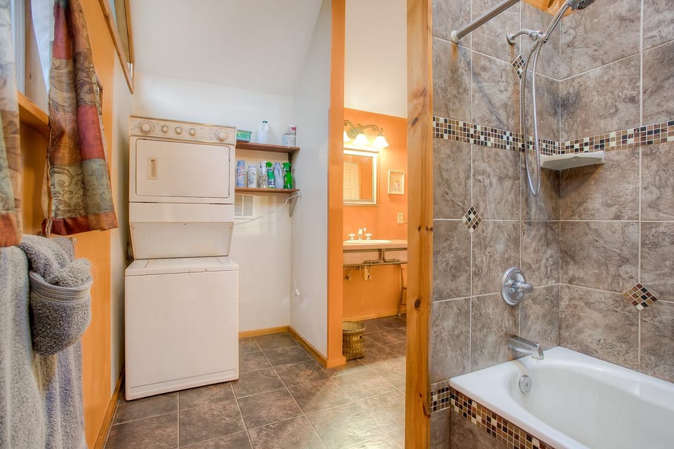 Bathroom includes a tub-shower and a stacked washer/dryer, along with complimentary eco-friendly sheets of detergent