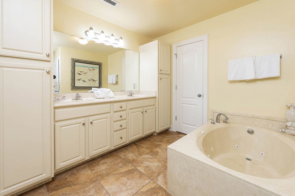 Luminous master bathroom featuring a luxurious jetted tub, walk-in shower, and ample counter space with elegant cabinetry