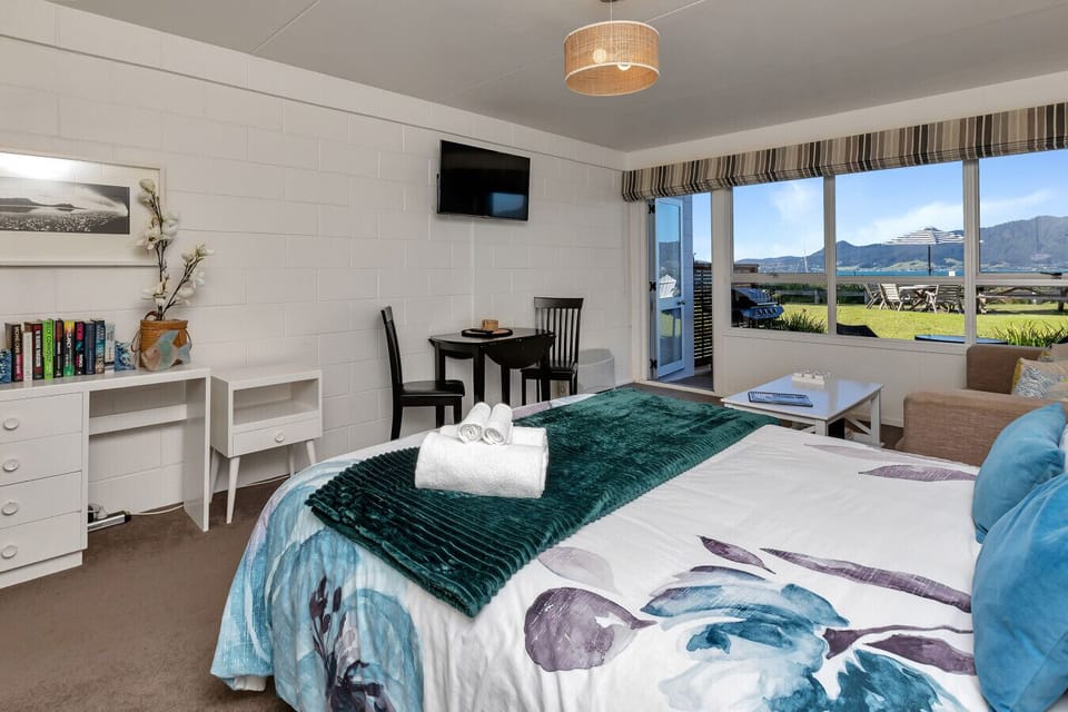 Another view of the studio showing the bed, the dining table, and the door which opens directly onto the front lawn.