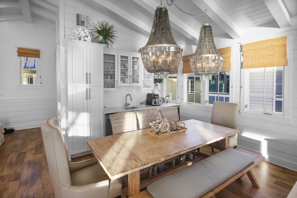 Coastal Dining Room with Natural Lighting, Designer Chandeliers, and Vaulted Beamed Ceilings