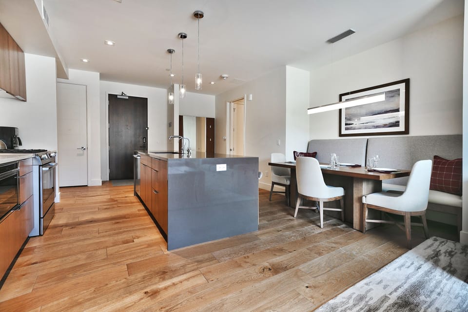 Solid quartz kitchen island with pendant drop lighting with the kitchen and dining area on either side