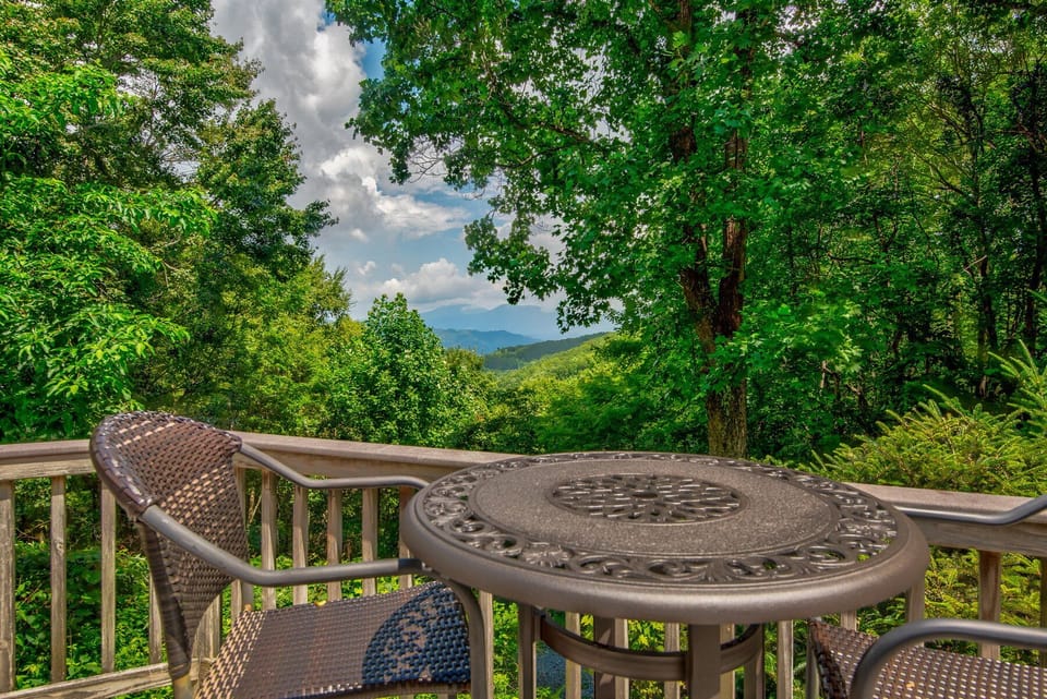 Morning coffee with a view. The deck at Misty Peak frames rolling Blue Ridge peaks through a canopy of summer green.