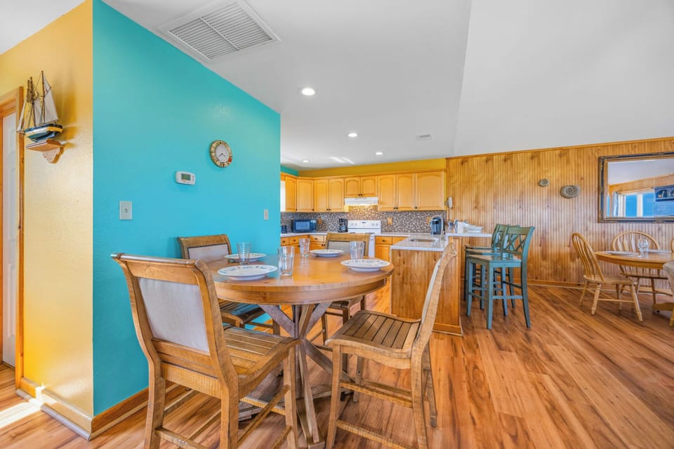 Gather in this coastal kitchen and dining space where warm wood tones and turquoise walls create a welcoming atmosphere. Cook in the fully-equipped kitchen or relax at the breakfast bar and spacious dining table.