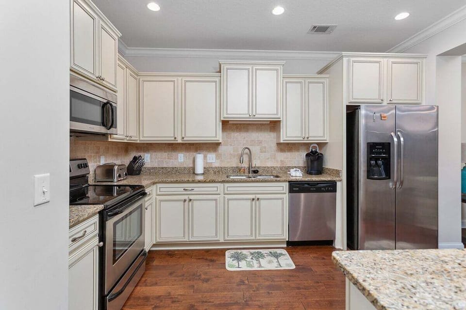 Kitchen with cream cabinets, granite counters, and stainless appliances
