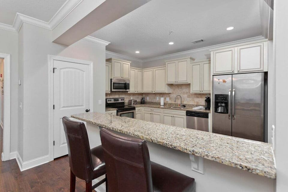 Kitchen with cream cabinets, granite island, and bar stools