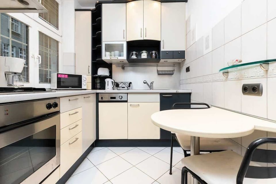 A sleek, contemporary kitchen with monochrome tones, stainless steel appliances, and modern black and white tiling, creating a sophisticated yet functional space.