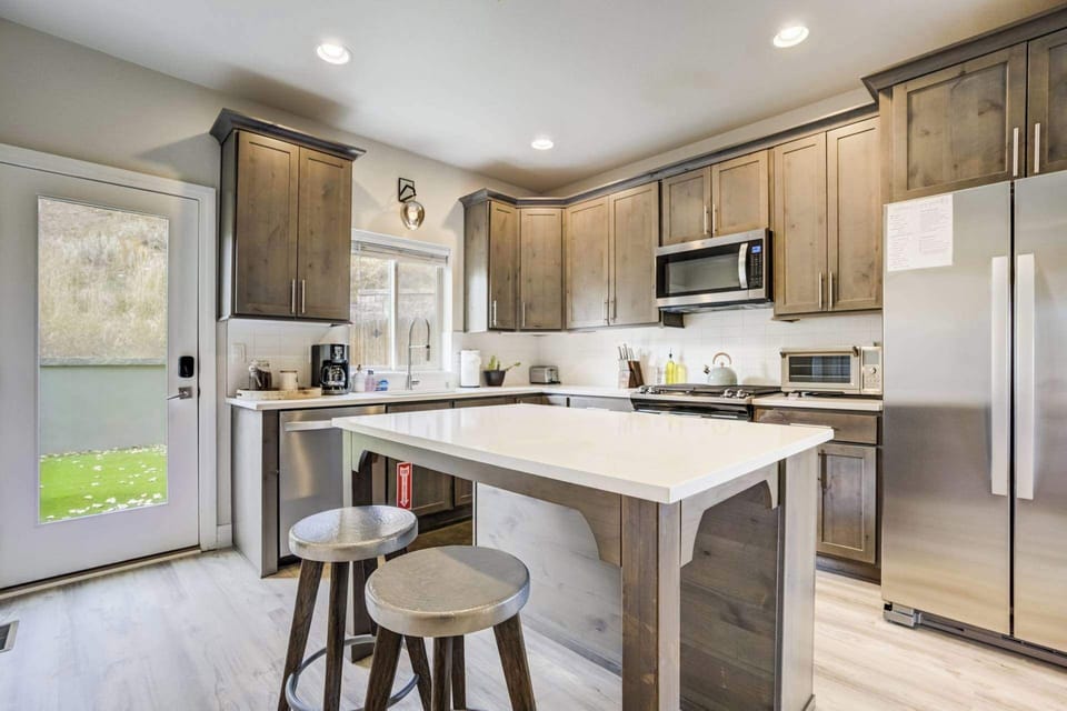 Clean, modern kitchen with a central island, bar stools, and stainless steel appliances. Prep meals, gather around the counter, or enjoy casual conversations while cooking in this bright, functional space.