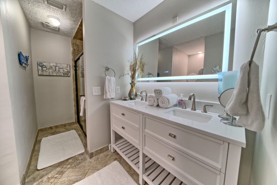 Pamper yourself in this spa-inspired bathroom with a sleek double vanity, backlit mirror, and a luxurious walk-in shower.