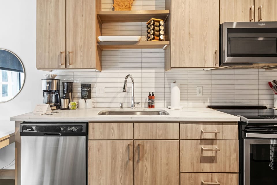 Your sleek kitchen features modern appliances and warm wood cabinetry, perfect for brewing morning coffee or preparing home-cooked meals.
