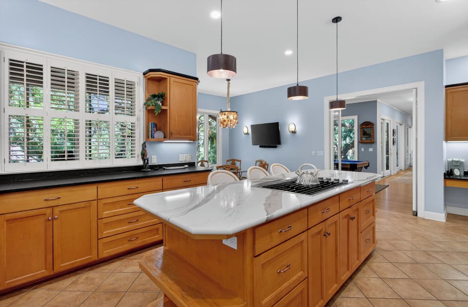 Picture yourself cooking your favorite meals in this spacious, sun-filled kitchen with warm wood cabinetry, sleek countertops, and a large island perfect for prepping or gathering around.