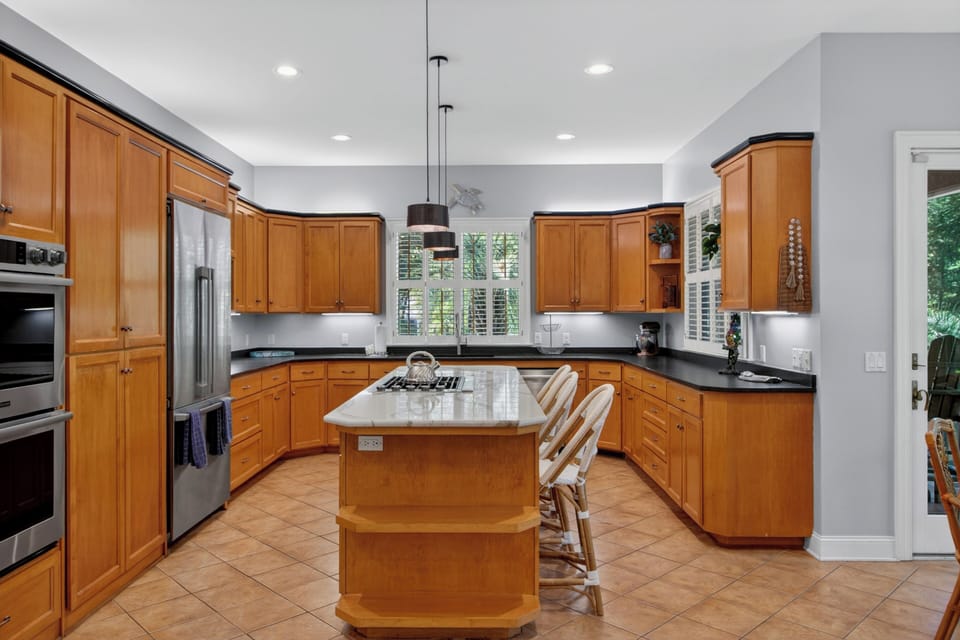 Your private chef's dream awaits in this spacious gourmet kitchen. Warm wood cabinetry, modern appliances, and a marble island invite you to cook, gather, and create lasting memories.
