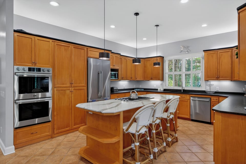 Your culinary haven awaits with rich wood cabinetry, stainless-steel appliances, and a spacious island—perfect for gathering over morning coffee or preparing your favorite meals during your stay.