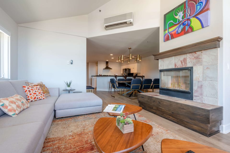 Relax in the modern living room with large flat screen TV, crackling fireplace, and private deck access