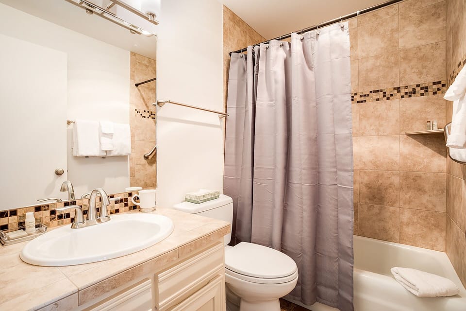 Step into your beautifully tiled bathroom, complete with elegant mosaic accents and fresh towels ready for your arrival. The spacious tub-shower combo offers the perfect retreat after a day of exploring.
