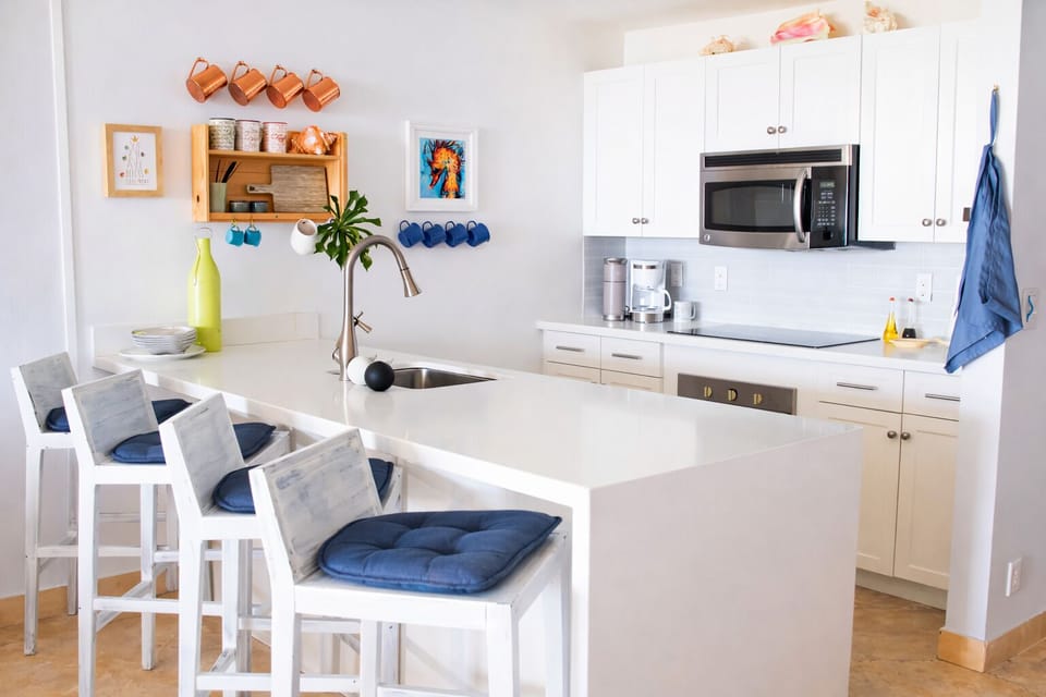 Modern kitchen with quartz counters, coffee station, and island seating.