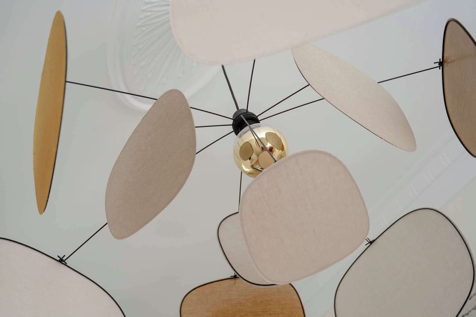A close-up of a lamp with abstract organic shapes in beige, white, and peach tones.