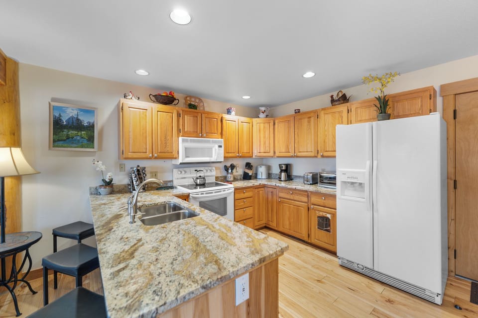 Cook memorable meals in your fully equipped kitchen featuring granite countertops, warm wood cabinetry, and modern appliances.