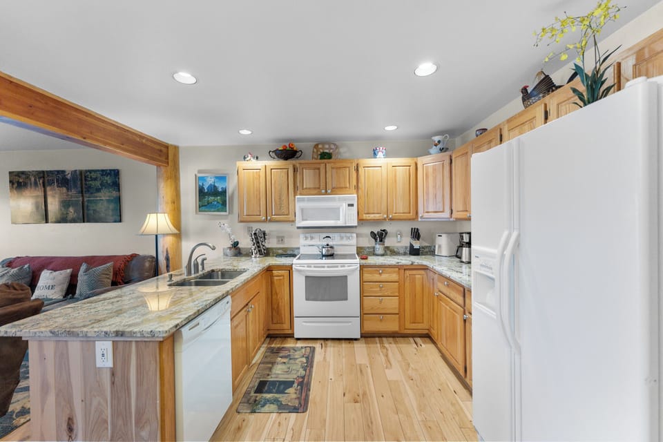 Step into your fully equipped kitchen with granite counters, modern appliances, and warm wood cabinetry—perfect for cooking meals together.
