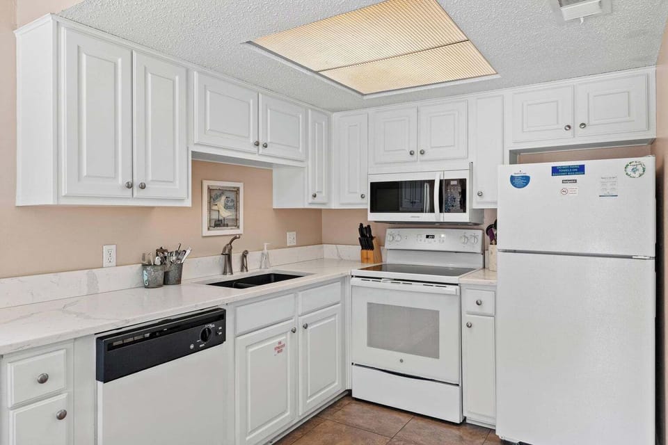 Fully equipped kitchen with stove, microwave, dishwasher, and utensils.