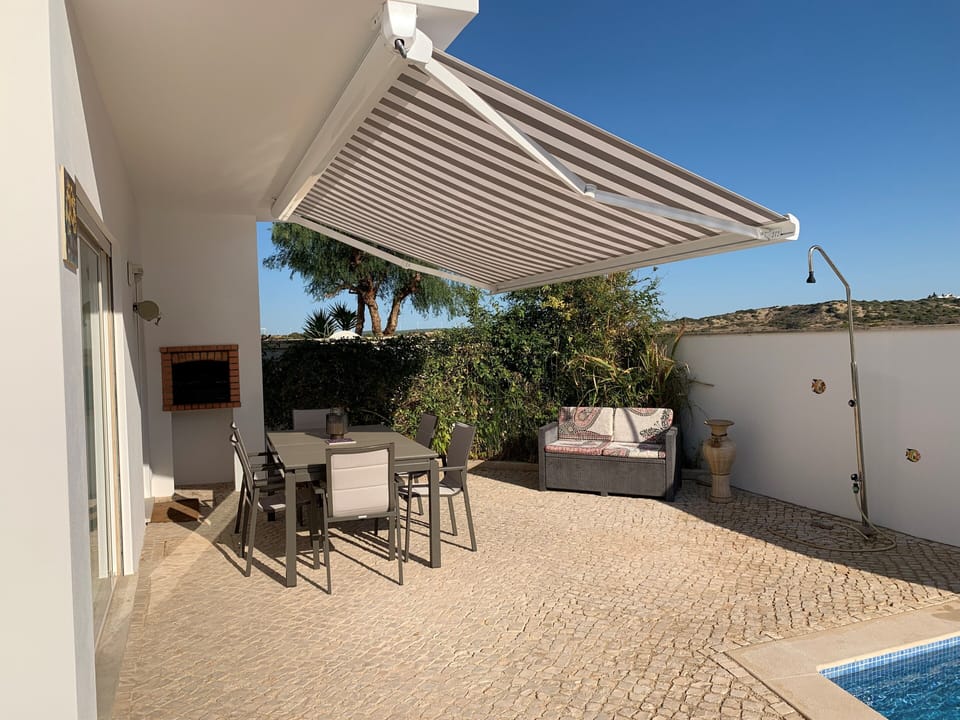 Back of the house with large shaded seating area and pool