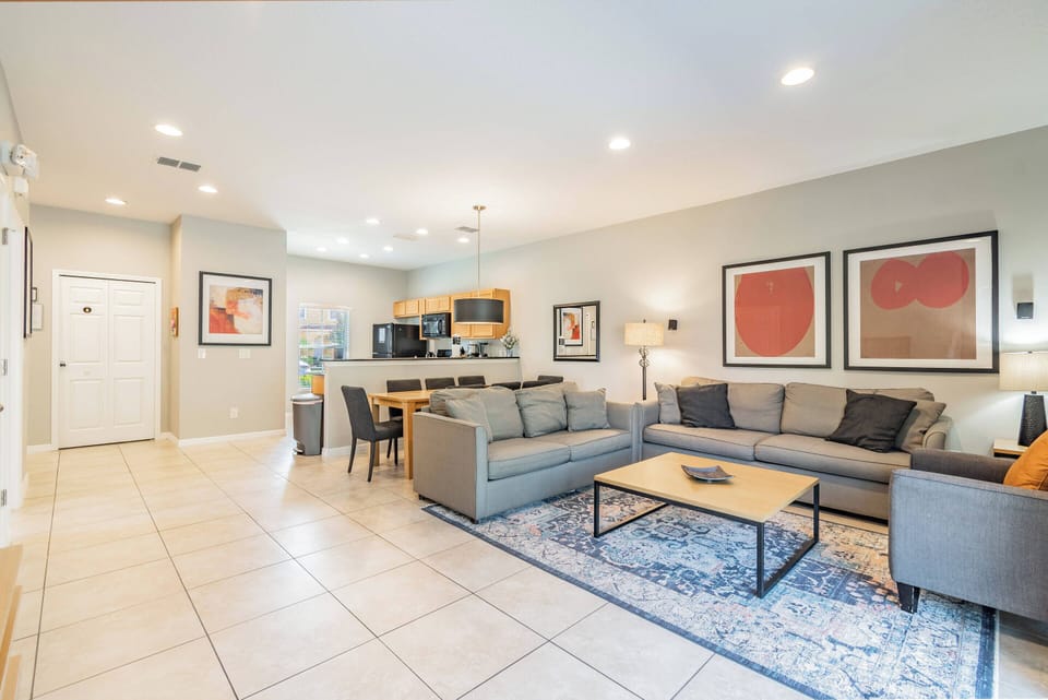 Step into this cozy living area featuring plush gray sofas that invite relaxation. A stylish blue area rug adds warmth underfoot, while vibrant artwork brightens the walls, creating a welcoming ambiance for your stay.