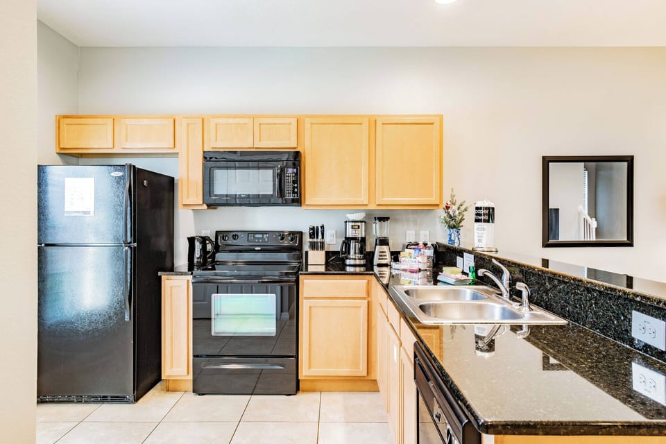 This bright kitchen boasts warm wood cabinetry, sleek black appliances, and a stunning granite countertop, making meal prep stylish and easy. Ample natural light creates an inviting atmosphere for all your cooking adventures.