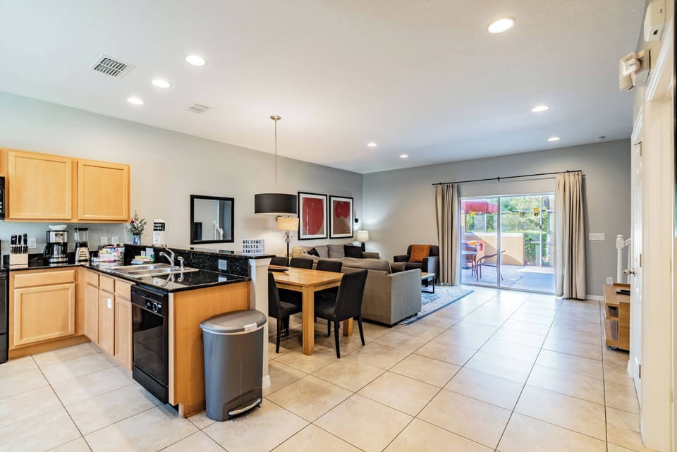 Enjoy a welcoming kitchen with warm wood cabinetry and sleek black countertops that flows into a cozy dining area. Large windows fill the space with natural light and offer lovely views, ideal for entertaining.